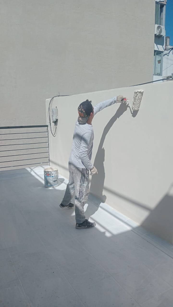 Operario aplicando pintura impermeabilizante en la pared de una terraza