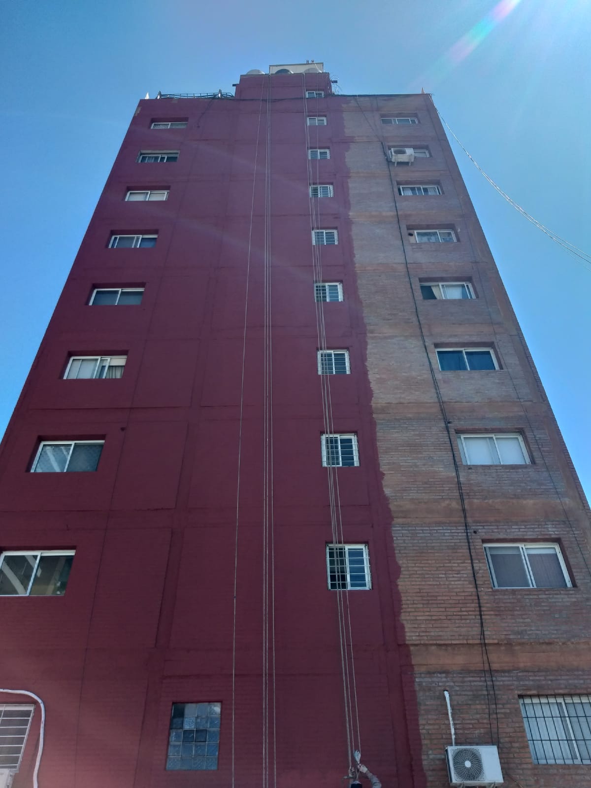 Torre de diez pisos con la medianera a medio pintar durante los trabajos de impermeabilización en silleta