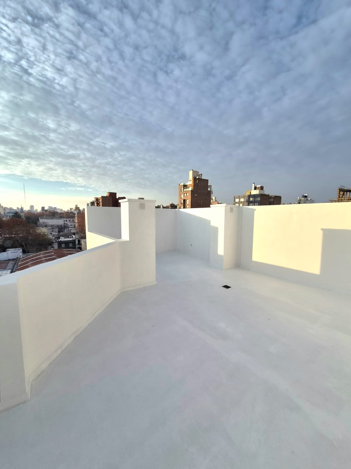Terraza de edificio impermeabilizada, con parapetos pintados y vista de la ciudad
